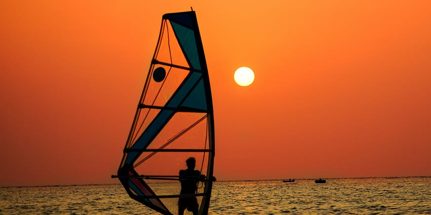 A man enjoys wind sailing off the coast of Kavaratti Island in Lakshadweep during a scenic sunset