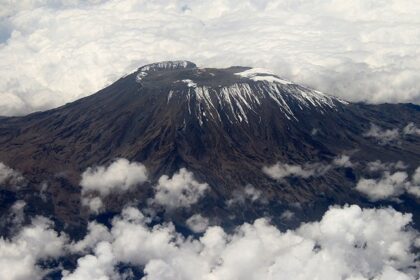 Mount Kilimanjaro with some snow on the top and mountain all surrounded by clouds