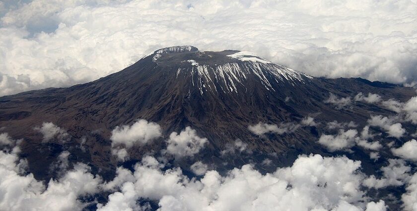 Mount Kilimanjaro with some snow on the top and mountain all surrounded by clouds