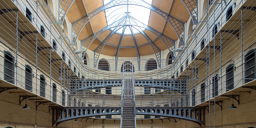 A picture of Kilmainham Gaol, featuring historic cells and a grand central hall.