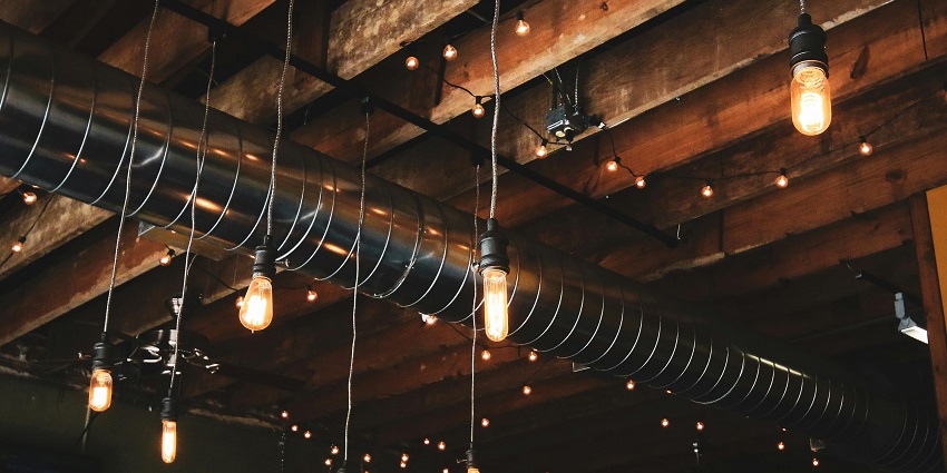 Black pendant-shaped lamp bulbs with small light bulbs hanging from the wooden roof, showing Warsaw nightlife.