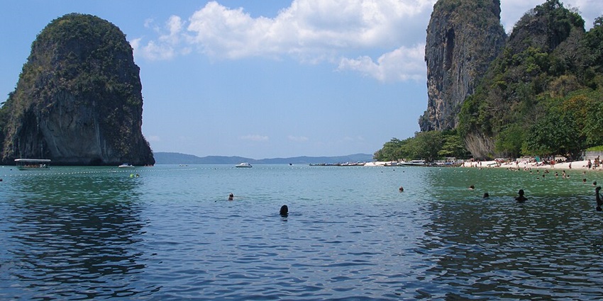 Tourists enjoy taking dips at scenic Railay Beach in Krabi, as suggested by Thailand Travel Guide.