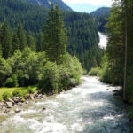 A view of Krimml Waterfalls cascading down rocks surrounded by lush green forest in Austria.