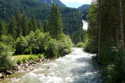 A view of Krimml Waterfalls cascading down rocks surrounded by lush green forest in Austria.