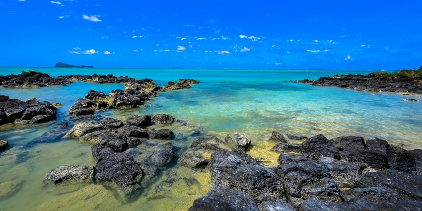 Some people are enjoying the ocean water and others are relaxing at the shoreside.