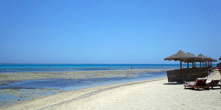 A pristine beach with clear water and sunbeds at one of the serene beaches in Egypt.