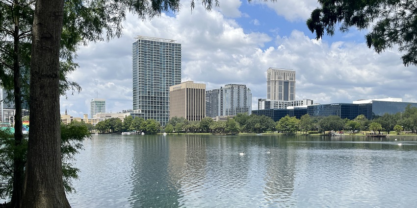 Lake Eola from the park with city buildings visible at a distance behind the green trees
