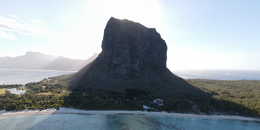 Le Morne Brabant with the Le Morne mountain casting shadow on the bright blue ocean.