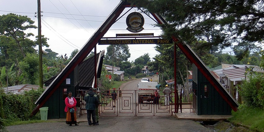 Entrance gate to Kilimanjaro National Park with a triangular structure and people