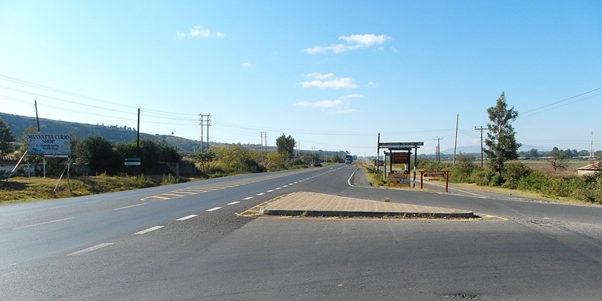 Crossroads to Nakuru, Naivasha and Nairobi with sign boards and a distant vehicle
