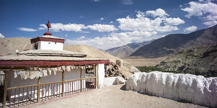 The scenic view of Kalachakra Monastery with lush greenery and the Himalayas.