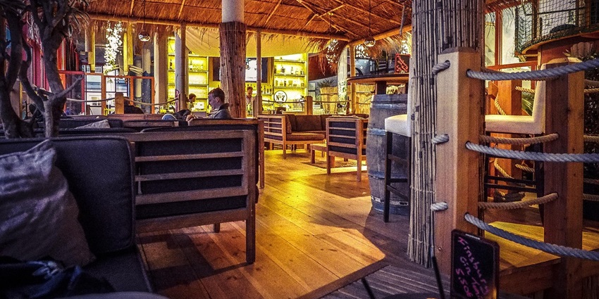 Inside a beach bar with wooden pillars and furniture, displaying Dar es salaam nightlife.