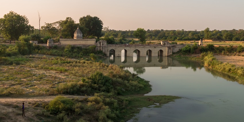 Bridge over Beta River with attached temple structure and lush surroundings in view