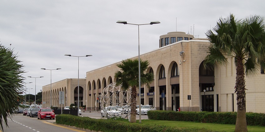 Malta International Airport with its modern architecture and vehicles parked outside.