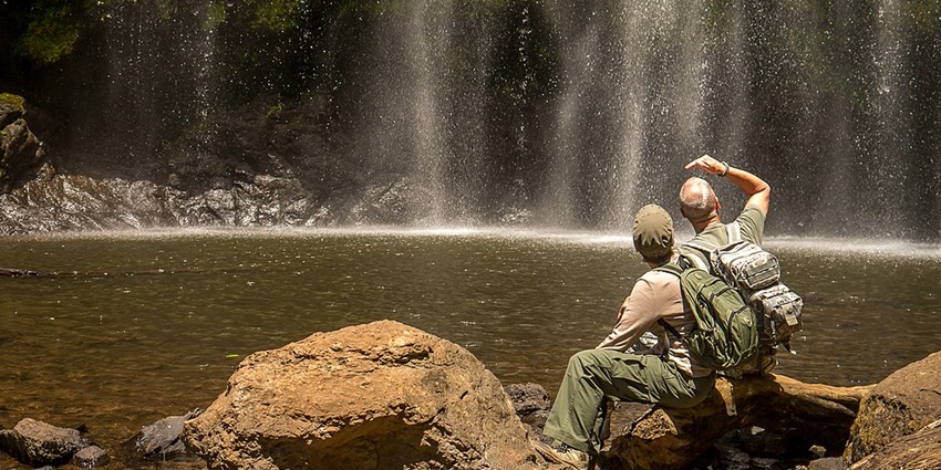 Two people sitting on the rocks near the water flowing in from the Maternui waterfall