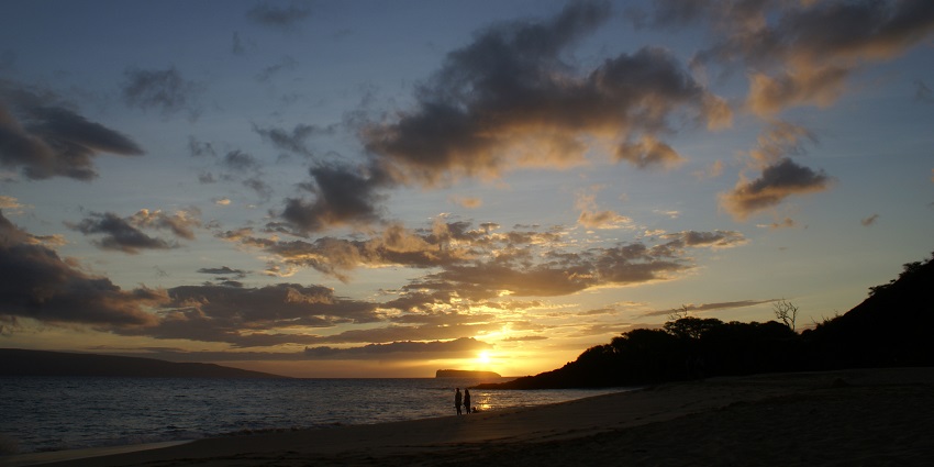 A couple is taking in the beautiful view of a serene subset at Makena Beach in Maui