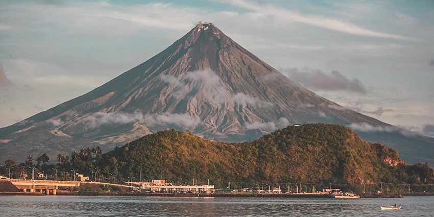 Perfectly symmetrical cone-shaped volcano towering above picturesque landscapes.