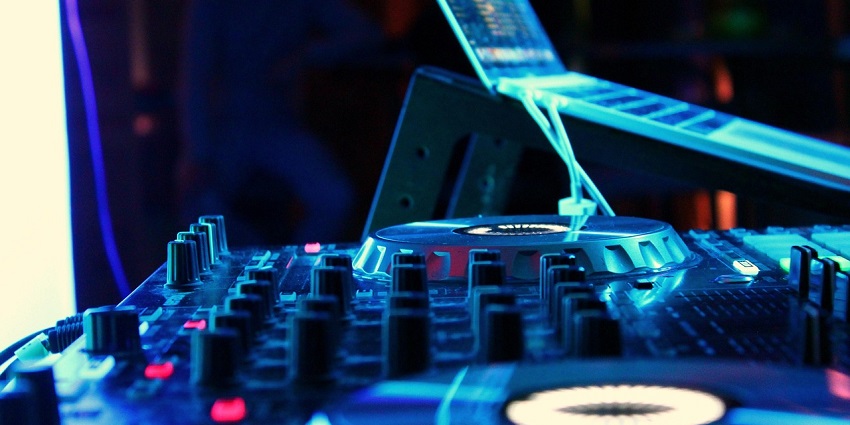 An image showing a DJ playing music to a lively crowd in a vibrant nightclub like Mojo Club.