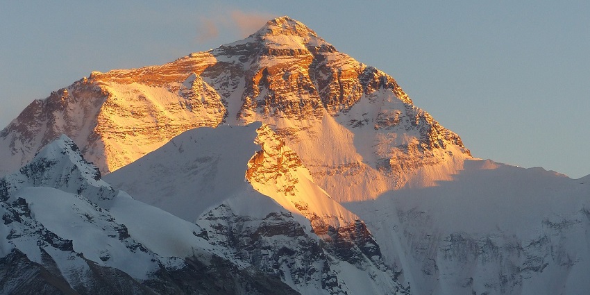 Snow-covered mountain range under a clear blue sky, with a panoramic view of nature.