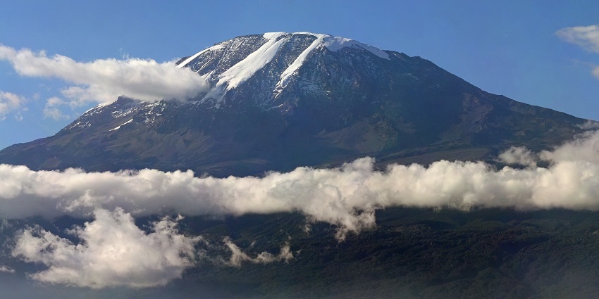 Fluffy layers of clouds float in front of a giant Mount Kilimanjaro in Tanzania