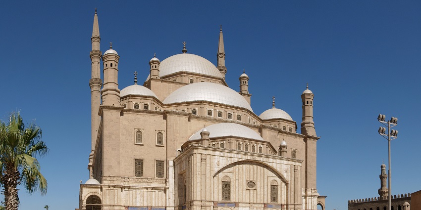 A distant view of the Muhammad Ali Mosque, outside which several people are presen