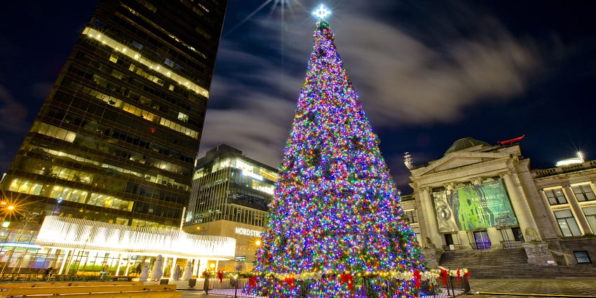 A large Christmas tree lighted with colourful lights and decorations outside a mall in Canada.