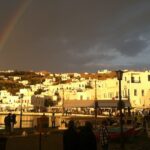 Mykonos with golden yellow sunlight hitting the white buildings, making a rainbow