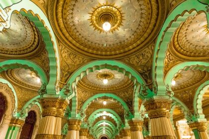 A wide view of a well-lit Mysore Palace with a dramatic background of clouds in Mysore, Karnataka.