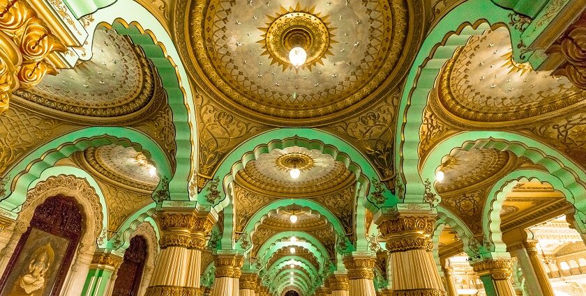 A wide view of a well-lit Mysore Palace with a dramatic background of clouds in Mysore, Karnataka.