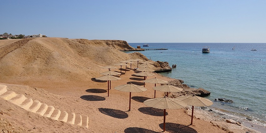 The sand staircase follows down to Naama Bay Beach, where several parasols are placed.