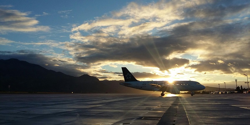 The silhouette of a plane on the runway with the setting sun and dark clouds in the background
