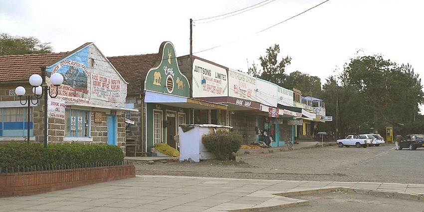 Busy street of Nanyuki town with multiple vehicles, people walking and distant Mount Kenya.