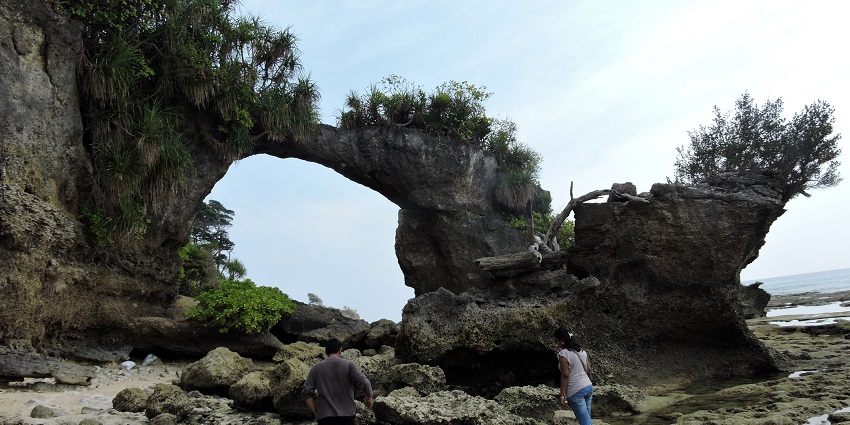 Tourists explore near a natural bridge by the sea on Neil Island, Andaman & Nicobar