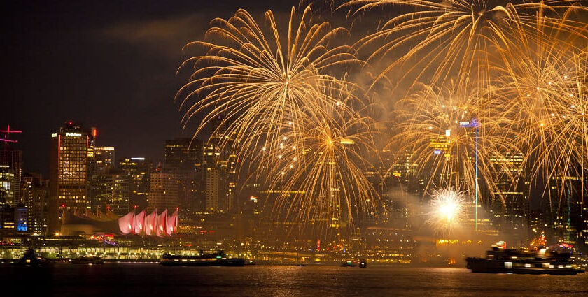 Fireworks burst in different colours above a cityscape during New Year celebrations.