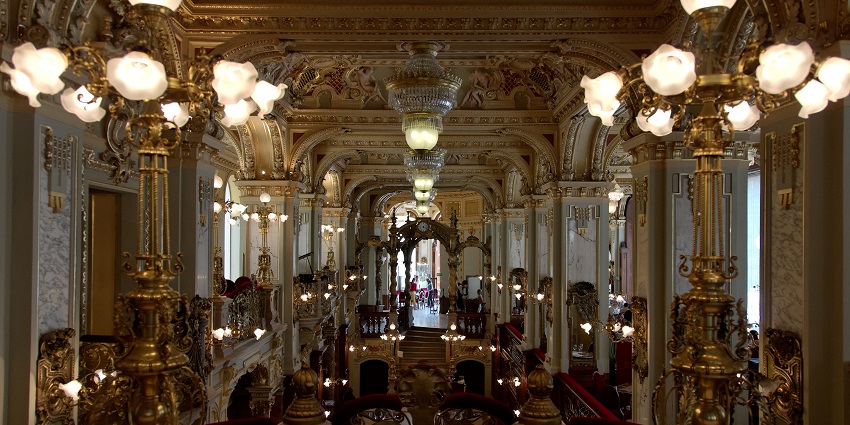 An image of an elegant interior of the New York Café with grand chandeliers.