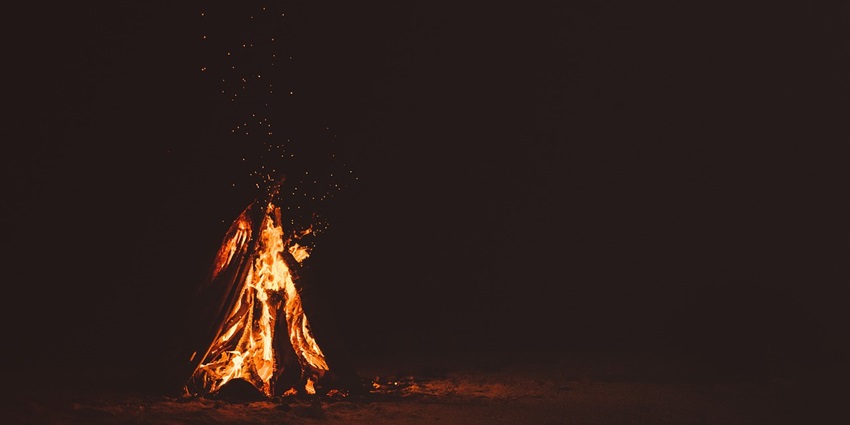 Woods burning in a bonfire with its flame emitting sparks visible against a dark background