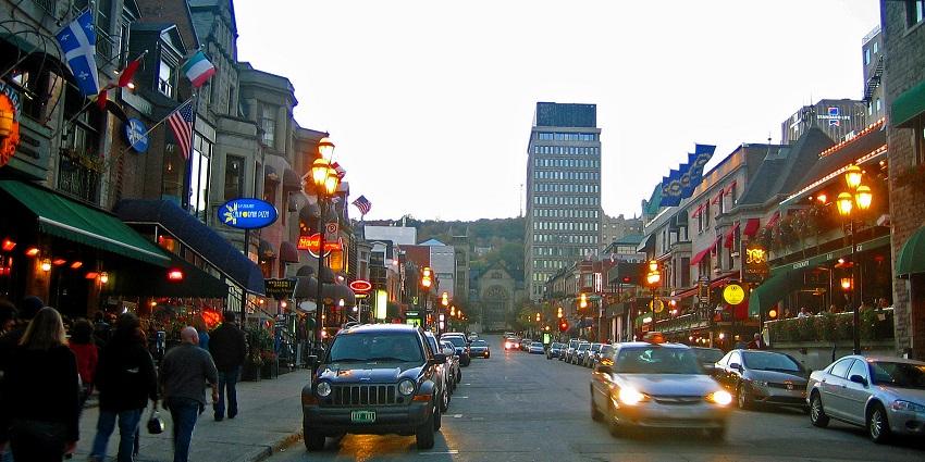Crescent Street in the evening with parked cars on the side of the street and people