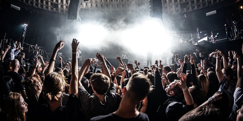 A group of people dancing in a nightclub, surrounded by dim lighting and a lively party atmosphere.