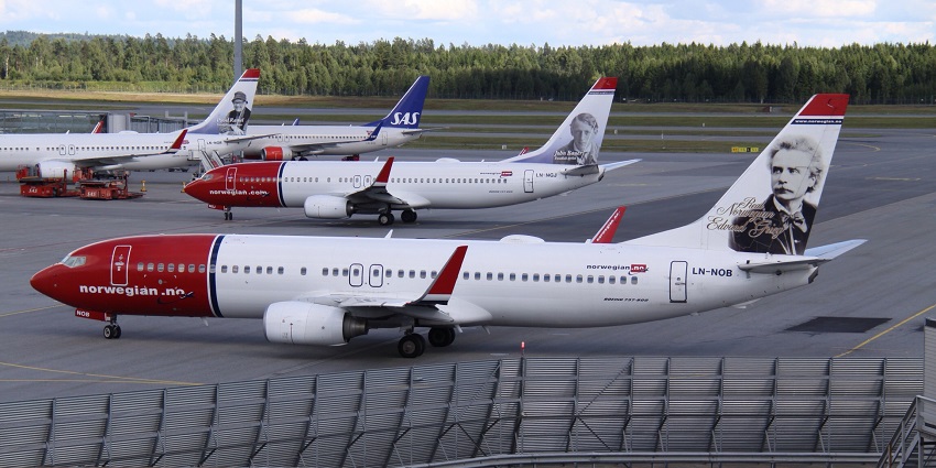 A Norwegian Air Shuttle Boeing 737 with winglets parked at the airport under a clear sky.