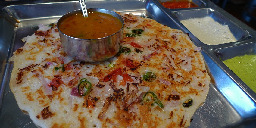 Onion Uttapam is a thick dosa-like dish, topped with onions, tomatoes, and green chillies.