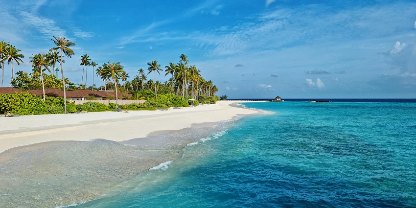 An image showing the serene Green Bowl Beach, under a clear blue sky and white sand