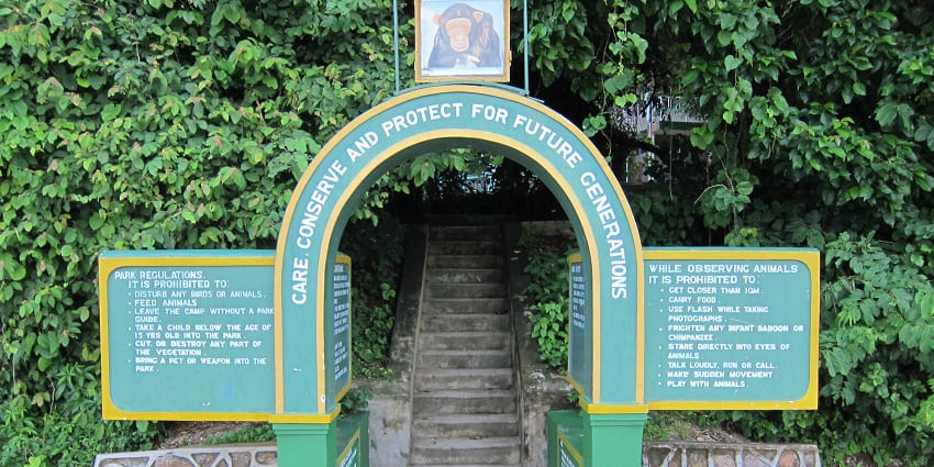 Entrance to Gombe National Park with signage, a chimpanzee photo, and a rules board