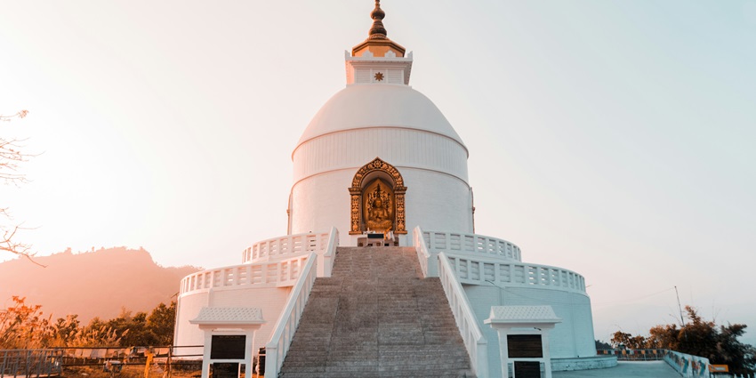 Image of a buddhist temple in white colour in Pokhra, Nepal amidst beautiful sun