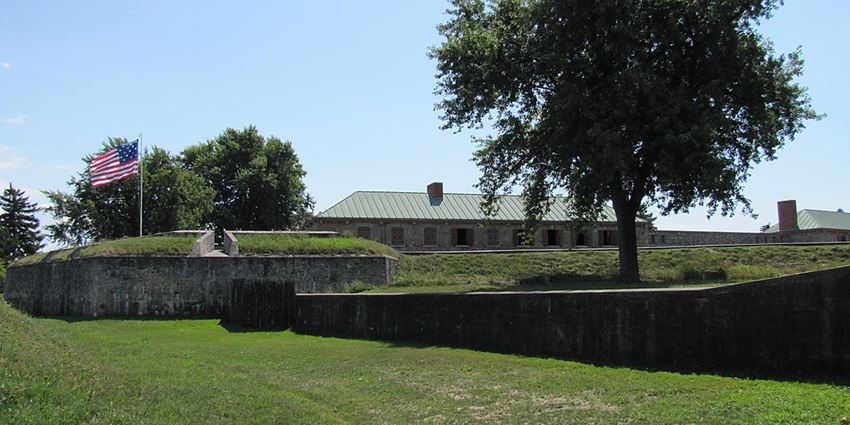 Historic buildings at Old Fort Erie in Ontario, surrounded by green grass and a cloudy sky.