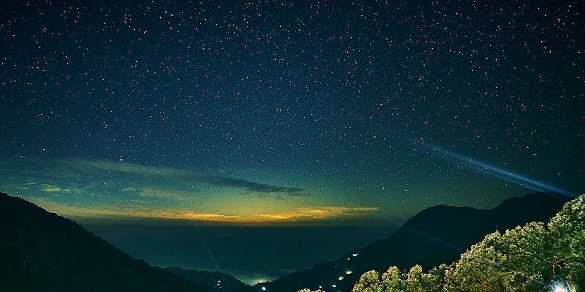 Image of green trees and mountains under blue sky during night time
