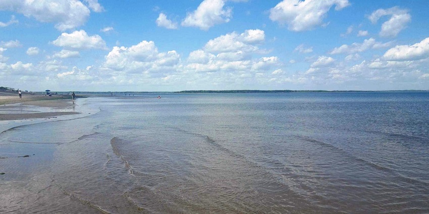 Calm waves are coming to the shore of Parlee Beach, New Brunswick, on a sunny day.