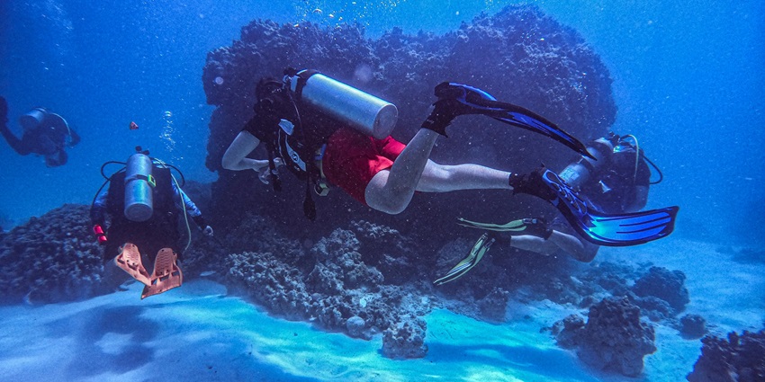 A person doing scuba diving in Mauritius with a heavy oxygen cylinder on his back.