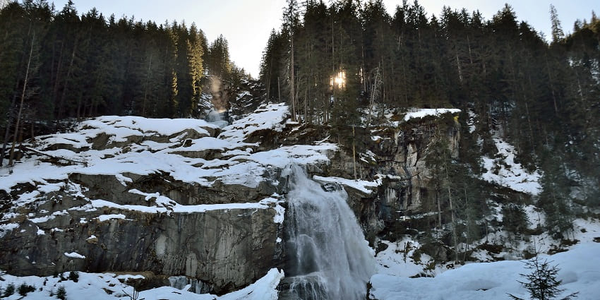 Image of Krimml Waterfalls in winter, with snow-covered surroundings and icy cascades.