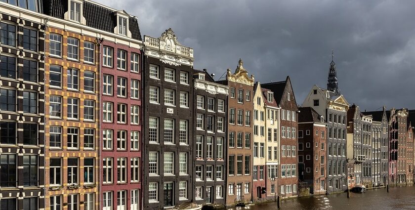 Colourful canal houses at golden hour in Damrak avenue in Amsterdam.