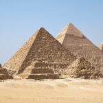 Giza Pyramids are standing tall on the rough, sandy landscape of a desert in Egypt.